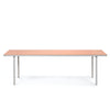 A large and minimalistic dining table in aluminium. Light pink coloured table top. White background.
