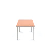 Minimalistic dining table made from aluminium. Bright pink table top. White background.
