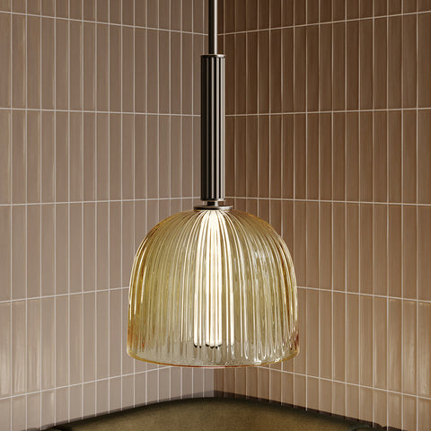 Glæsilegt og fágað loftljós úr dökk brenndu bronze með brass lituðum glerkúpli. Ljósbrúnar flísar á vegg í bakgrunni. Kveikt er á ljósinu.