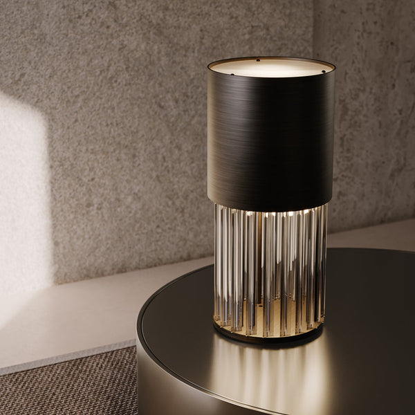 Stórglæsilegur og skúlptúrískur borðlampi úr dökk brenndu bronsi og crystal. Lampinn stendur á borði. Grá dröppuð litapalletta. Kveikt er á lampanum.