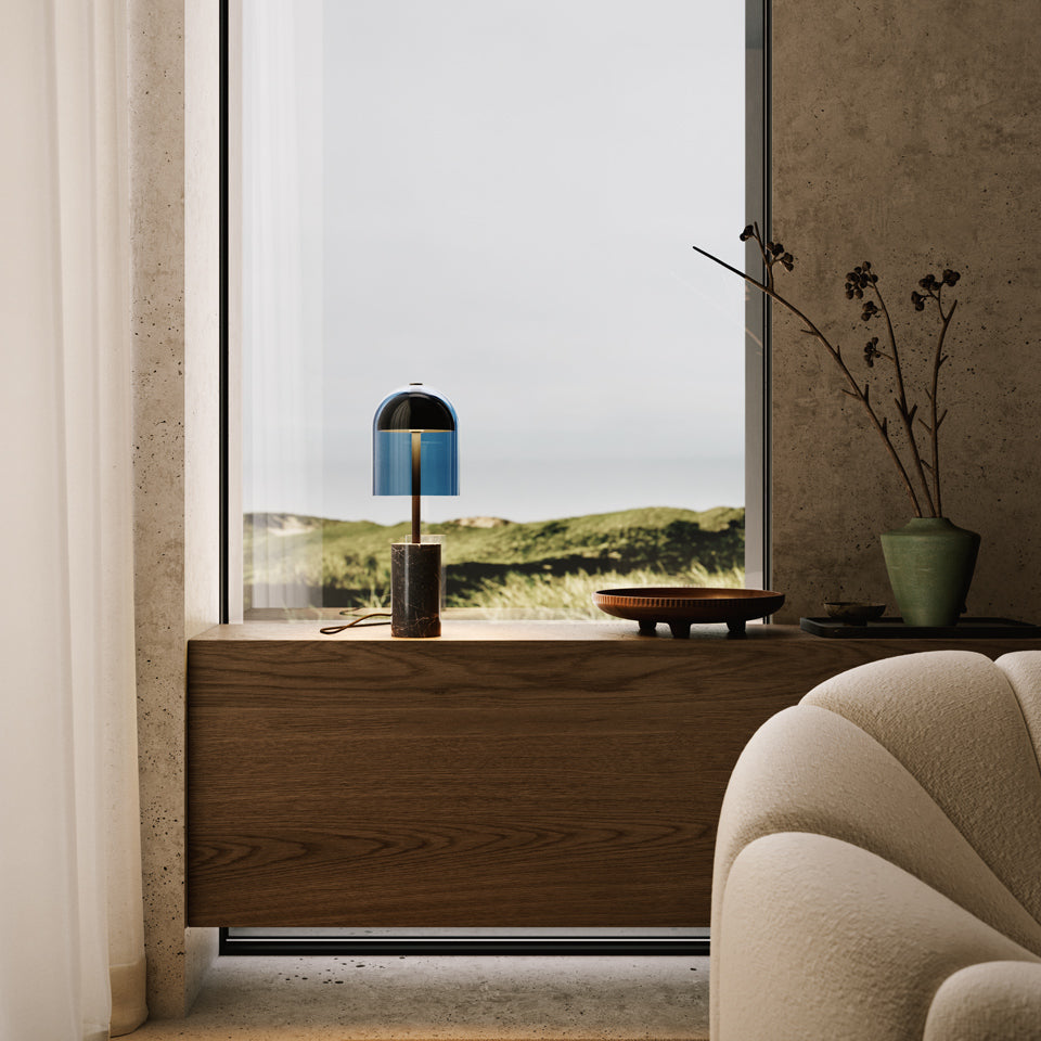 Dásamlegur borðlampi frá Venicem stendur úti í glugga. Undirstaða úr svörtum marmara. Brass. Blár glerskermur.