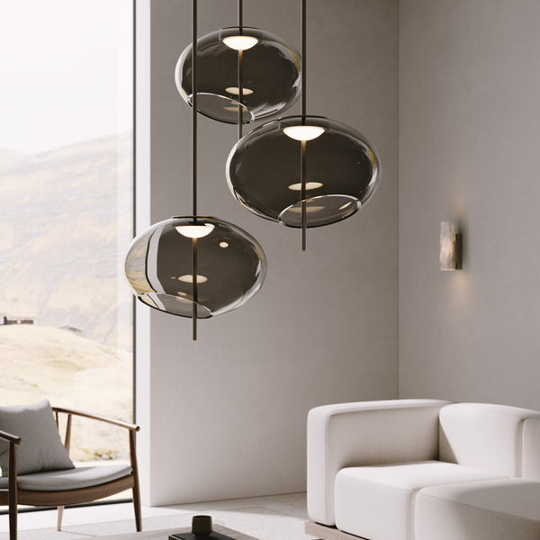 Þrjú, stór glæsileg loftljós af sömu tegund frá Venicem hanga í bjartri stofu. Dökkt gler. Hvítir veggir og gluggi í bakgrunni. Hvítur sófi. Kveikt er á ljósunum.