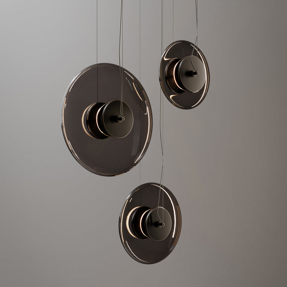 Þrjú glæsileg og disklaga loftljós frá Venicem úr reyklituðu gleri hanga saman. Grár bakgrunnur.