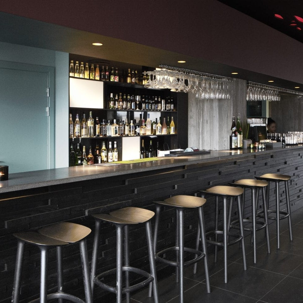 Svartir barstólar upp við svartan bar.