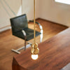 Gold pendant light hanging above a wooden table with a blurred chair in the background