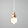 Modern pendant light with copper fixture and white bulb on a gray background