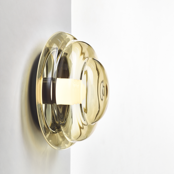 Fallegt munnblásið veggljós í amber lit. Ljósið er á hvítum vegg. Kveikt er á ljósinu.