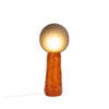 A earthy red ceramic floor lamp on a white background. Handmade, smokey grey glass diffuser. The lamp is lit.
