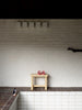 Photo inside. Narrow shot. Tiles on the wall. In the center of the image is the 002 Ast stool by Vaarnii.