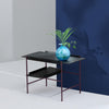 Danish design. Tray table. Black wooden trays on a burgundy metal frame. Blue wall.